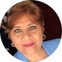 Una mujer de pelo corto castaño claro y ojos azules sonríe a la cámara. Lleva una americana azul claro y los labios pintados de rosa. El fondo oscuro, ligeramente difuminado, deja entrever su experiencia en ortopedia deportiva.